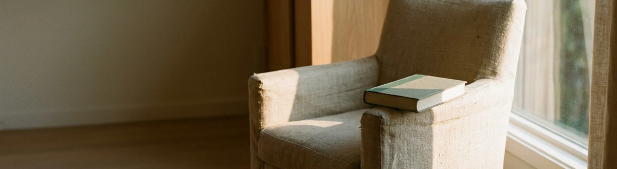Кресло у окна с книгой на подлокотнике
